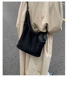 Detail of black suede hobo bag with a matching round coin purse on a long trench coat