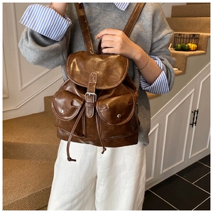 Detail of vintage brown leather backpack with two front pockets and silver twist locks