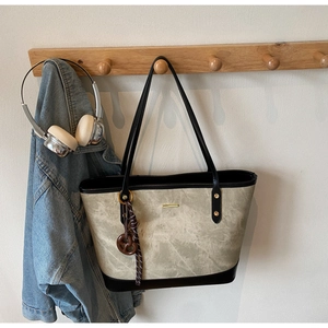 Detail of grey marbled tote bag with black accents and decorative brown pendant