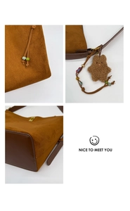 Detail of brown suede bucket bag featuring colorful beaded drawstrings and a plush charm