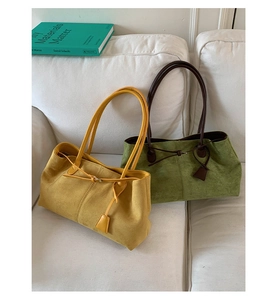 Dettaglio di borse tote in camoscio giallo zenzero e verde muschio su divano bianco