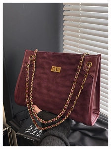 Détail macro du sac cabas en daim bordeaux avec matelassage et bandoulière chaîne dorée