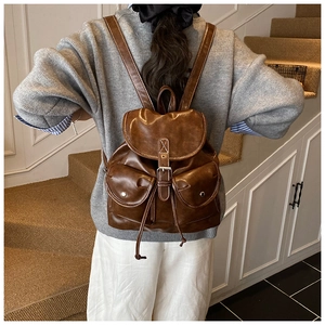 Detail shot of vintage brown PU leather backpack with buckle straps on indoor stairs