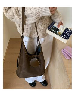 Detail of dark brown suede hobo bag with round charm and adjustable shoulder strap
