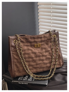 Détail du sac cabas en daim marron foncé avec motif matelassé et chaîne dorée