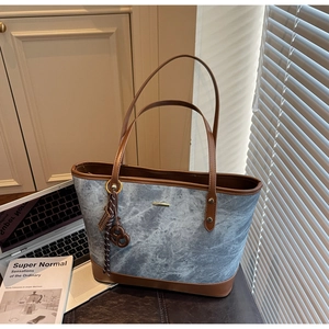 Detail of a large marble pattern canvas tote bag with brown leather trim and gold hardware