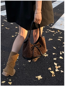 Detailed view of leopard print tote bag with black leather bow on an autumn street