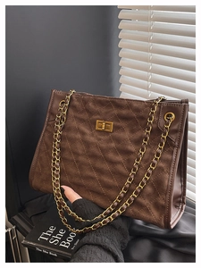 Detailed view of quilted suede tote with gold square twist lock and metal chain strap