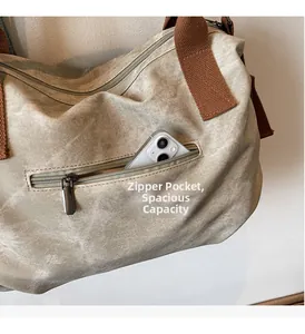 Close-up of front zipper pocket on khaki canvas tote bag holding a smartphone