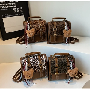 Detail of four leopard print mini backpacks with bear charms and metal buckles