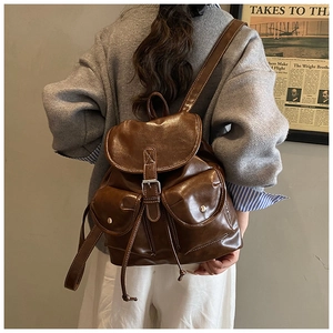 Detail of vintage brown PU leather backpack with metallic buckles and side pockets