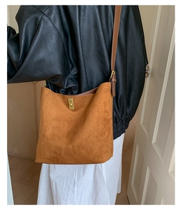 Detail view of vintage brown matte bucket bag with golden metal twist lock on a model