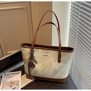 Detail of minimalist tote bag with metal logo, brown trim and woven rope decor