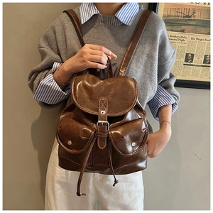 Brown vintage leather backpack shown on model featuring classic buckled front pockets