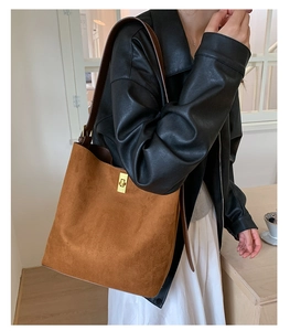 Detail of caramel suede tote bag with golden twist lock and dark brown leather strap