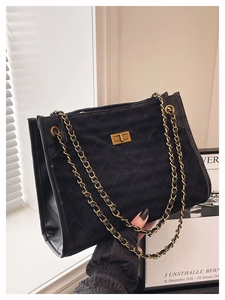 Détail du sac à bandoulière en daim matelassé noir avec chaîne dorée et fermoir pivotant