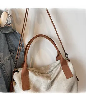 Detail of canvas tote bag with brown straps, metal buckles and zipper closure