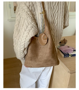 Detailed close-up of brown frosted leather bucket bag with shoulder strap and charm