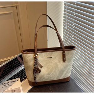 Detailed view of bicolor suede tote bag featuring a leather base and pretzel charm