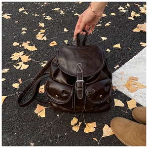 Detail of dark brown vintage backpack with contrast stitching on ginkgo leaves background