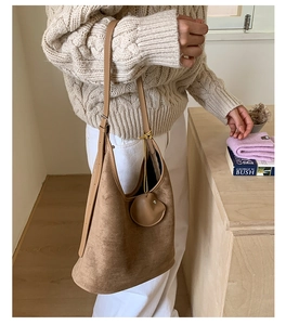 Close-up of brown suede hobo bag with round decorative tag and comfortable wide shoulder strap