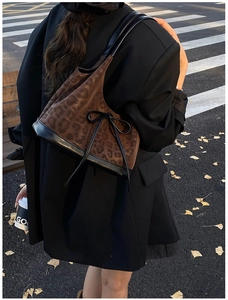 Close-up of leopard print patchwork tote bag with bow detail in an urban autumn setting