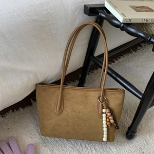 Close-up of brown suede tote bag featuring a bohemian beaded charm and leather straps