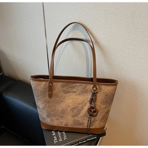 Detail of a brown tote bag with vintage texture leather and a stylish knot pendant
