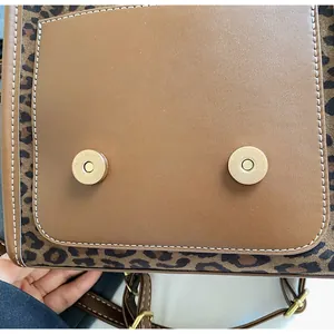 Close-up of leopard print backpack featuring dual magnetic closures and brown leather detail