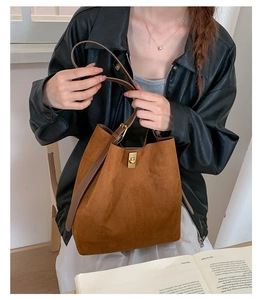 Detail of vintage suede bucket bag with gold metal clasp and brown leather strap