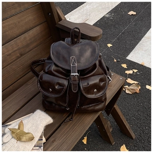 Detail view of vintage dark brown faux leather backpack with metallic buckle on wooden bench