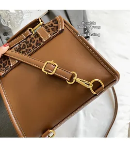 Detail of durable golden hooks and leopard print fabric on the brown leather backpack