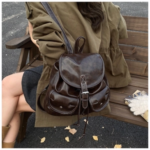 Detail of dark brown vintage leather backpack with front pockets and white stitching detail