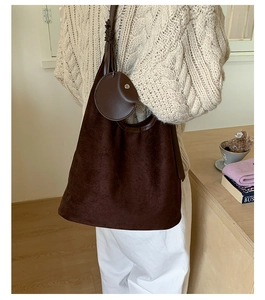 Detail of large brown suede shoulder bag with matching round coin purse on a model
