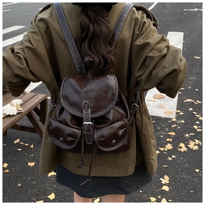 Detail of vintage dark brown backpack with white stitching and silver metal buckles