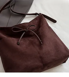 Detail of soft dark brown suede shoulder bag with decorative bow and stitching