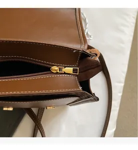 Close-up of smooth metal zipper and white stitching detail on brown leopard print bag