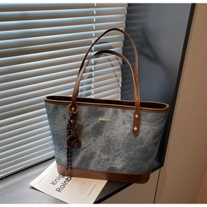Detail of blue marble tote bag featuring brown leather trim and gold metal ring hardware