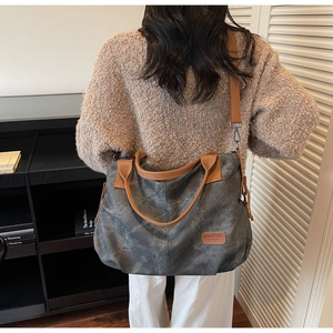 Detail of vintage canvas tote bag with brown straps and logo on washed grey fabric