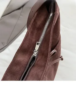 Close-up of the smooth silver zipper and suede texture on a vintage brown tote bag
