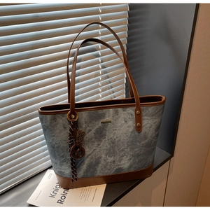Detail of blue-grey marble texture tote bag with brown leather handles and metal hardware