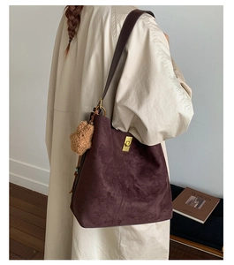Detail view of deep purple suede bucket bag with gold lock and plush bear charm
