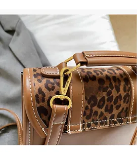 Detail of durable gold metal hook on leopard print canvas and brown leather backpack