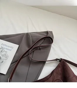 Detail of dark brown suede shoulder bag with slim leather straps and metal hardware