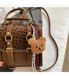 Detail of leopard print backpack with gold buckles and brown plush bear charm