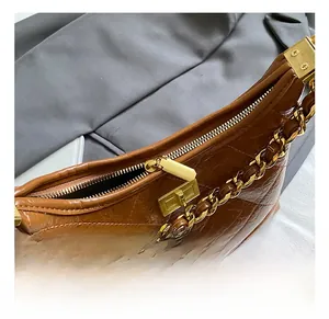 Gros plan du sac en cuir croco marron avec chaîne dorée et fermoir métallique chic