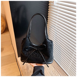 Detailed close-up of leopard print handbag featuring a decorative black leather bow