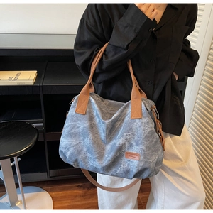 Detail of blue canvas tote bag with adjustable brown shoulder strap on model