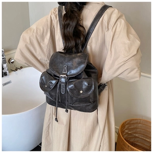 Detail of a vintage black waxed leather backpack with drawstring and silver buckle