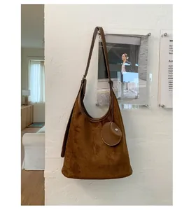 Detail view of brown faux suede hobo bag with a matching round coin purse on white wall